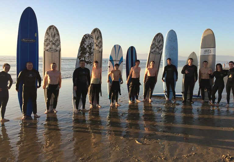 Group of surfers stand in front of their boards at el Porto beach in Manhattan Beach Los Angeles County