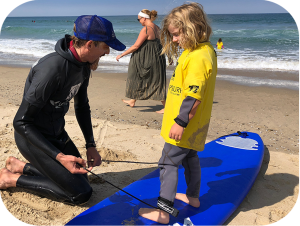 an expert surfing instructor teach a small child the proper surf stance at Camp Surf Manhattan beach kids summer camp