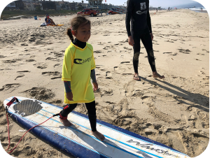 a young girl learning the proper surfing stance at Camp Surf kids summer beach camp